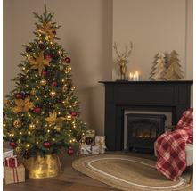 Festlich geschmückter Weihnachtsbaum in einem Wohnzimmer mit Kamin und Geschenken.