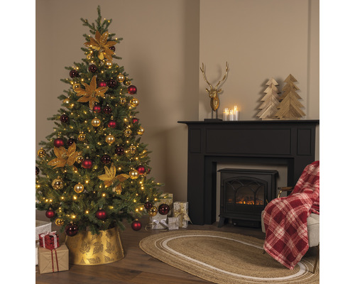 Festlich geschmückter Weihnachtsbaum in einem Wohnzimmer mit Kamin und Geschenken.