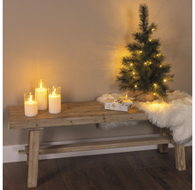 Dekorative Szene mit Bank, Kerzen, kleinem Weihnachtsbaum, Geschenk und Fellteppich für eine festliche Atmosphäre