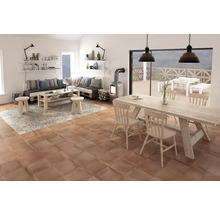 Wohnzimmer mit Holztisch, Stühlen, Sofa, Teppich und Kaminofen auf Terrakottafliesen