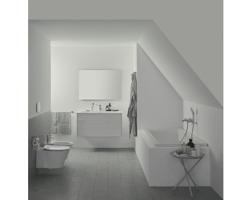 Helles Badezimmer mit Badewanne, Waschtisch und Toilette unter einer Dachschräge.