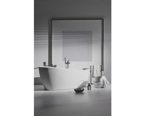 Freistehende Badewanne mit Armatur, Handtuchhalter und Badutensilien in einem Badezimmer.