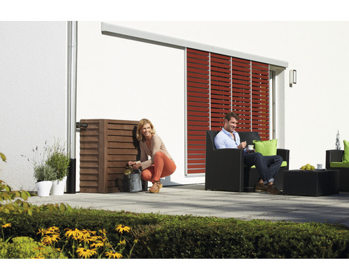 Szene mit einer Frau, die Wasser aus einem Regenspeicher schöpft, und einem Mann, der in einem Gartenstuhl sitzt