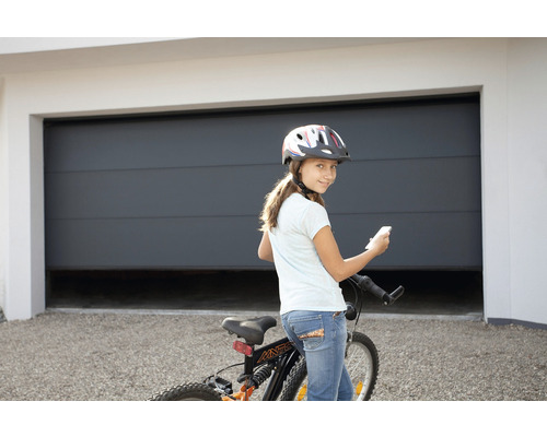 Mädchen mit Fahrrad und Helm vor einer Garage mit Garagentoröffner