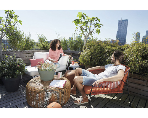 Szene mit Frau auf Terrassensofa und Mann im Sessel auf einer Dachterrasse mit Tisch und Pflanzen