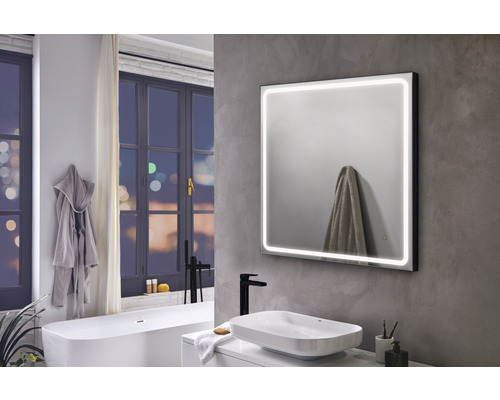 Modernes Badezimmer mit beleuchtetem Spiegel, Waschbecken und Badewanne.