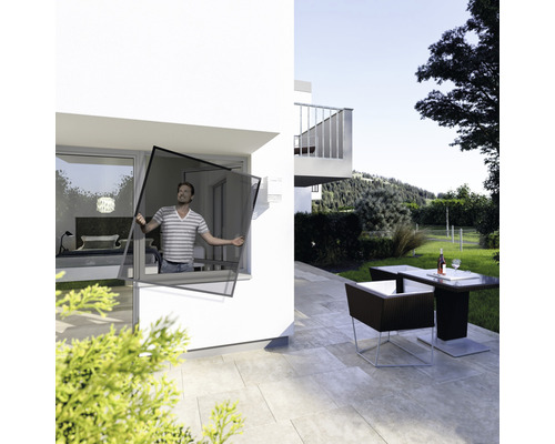 Mann montiert Insektenschutzgitter am Fenster eines Hauses mit Terrasse