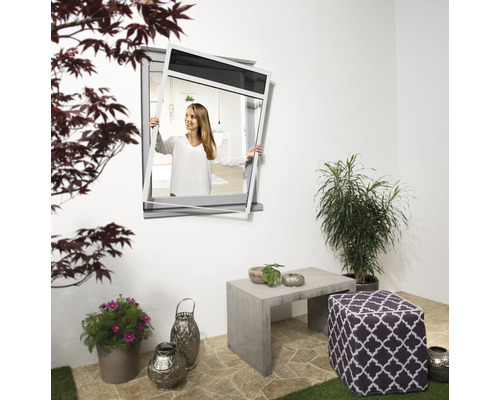 Eine Frau öffnet ein Fenster in einem Garten mit Pflanzgefäßen, einem Hocker und einem Tisch.