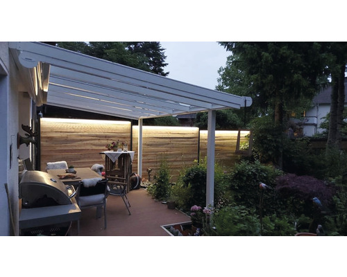 Terrasse mit Überdachung, Tisch, Stühlen und Beleuchtung.