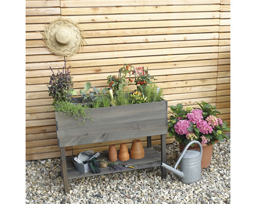 Hochbeet aus Holz mit Kräutern, Tomaten und Gartenutensilien