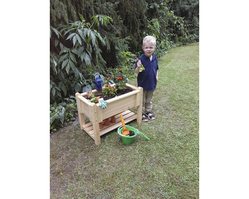 Hochbeet aus Holz mit Pflanzen, Gartenzubehör und einem Kind im Garten.