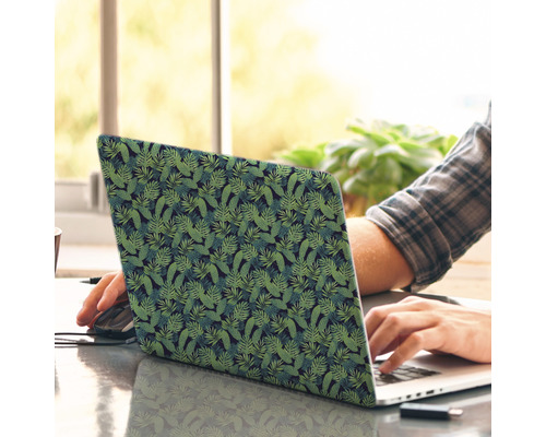 Ein Laptop mit tropischem Blattmuster wird von einer Person benutzt