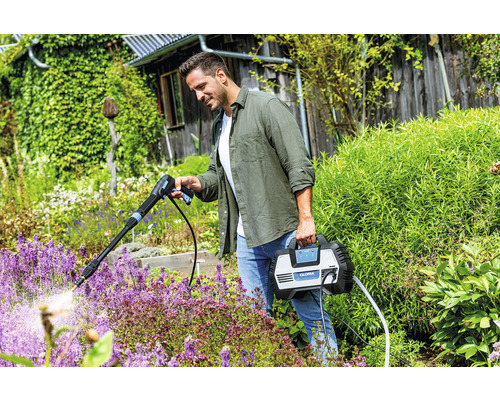 Mann benutzt Gloria Hochdruckreiniger im Garten zur Bewässerung von Pflanzen.