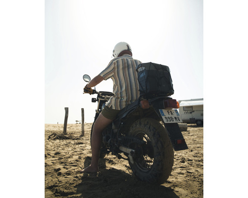 Mann mit Helm auf einem Motorrad am Strand