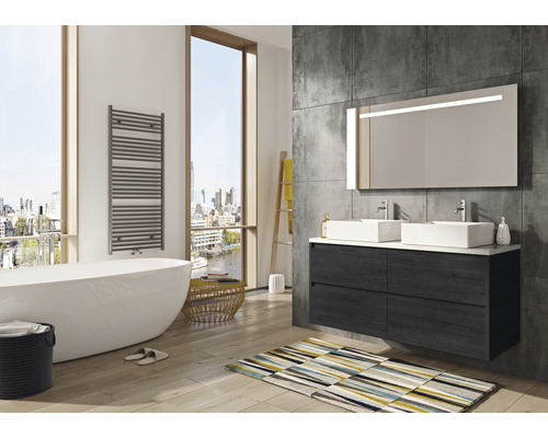 Badezimmer mit Badewanne, Waschtisch mit zwei Waschbecken, Spiegel mit Beleuchtung und Handtuchwärmer.