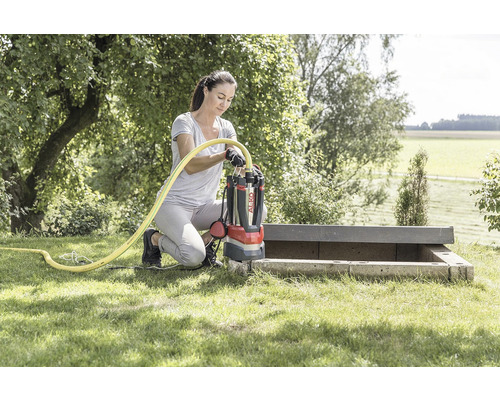 Frau schließt eine AL-KO Tauchpumpe im Garten an einen Schlauch an