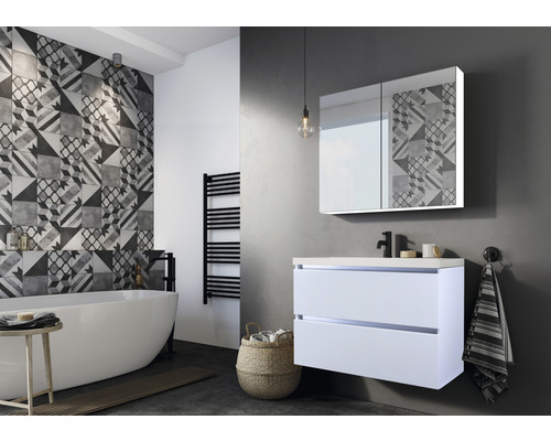 Badezimmer mit Badewanne, Waschtischunterschrank und Spiegelschrank mit geometrischem Muster