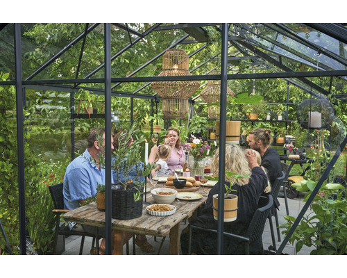 Gewächshaus mit Tisch und sitzenden Personen
