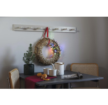 Szene mit Tisch, Stühlen, Strohkranz mit Lichterkette, Pflanze, Geschirr und Garderobenleiste