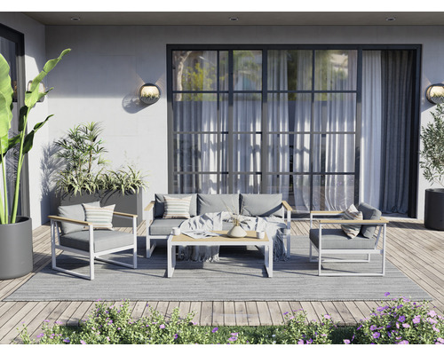 Terrasse mit Sitzgruppe, bestehend aus Sofa, Sesseln und Tisch auf einem Teppich