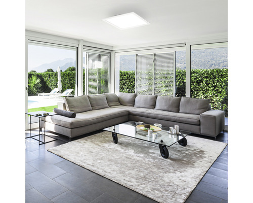 Helles Wohnzimmer mit großem Sofa, Teppich und quadratischer Deckenleuchte