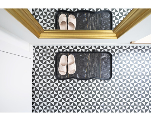 Flur mit Schuhablage und Hausschuhen vor einer Wand mit geometrischem Muster