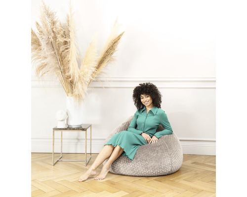 Frau sitzt in einem grauen Sitzsack in einem hellen Raum