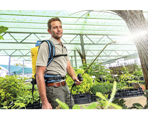 Mann verwendet eine Rückenspritze zur Pflanzenpflege im Gewächshaus.