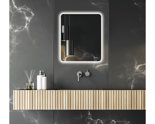 Modernes Badezimmer mit beleuchtetem Spiegel, Waschtisch und Armaturen vor dunklem Hintergrund