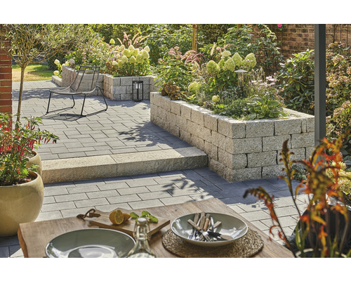 Gestalteter Garten mit Pflastersteinen, Sitzgelegenheit und erhöhten Pflanzbeeten