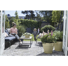 Terrasse mit Sitzgruppe, Tisch und bepflanzten Blumentöpfen in einem Garten.