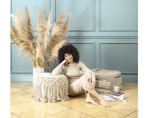 Dekorative Szene mit Frau, Ziergras und Pouf auf Holzboden