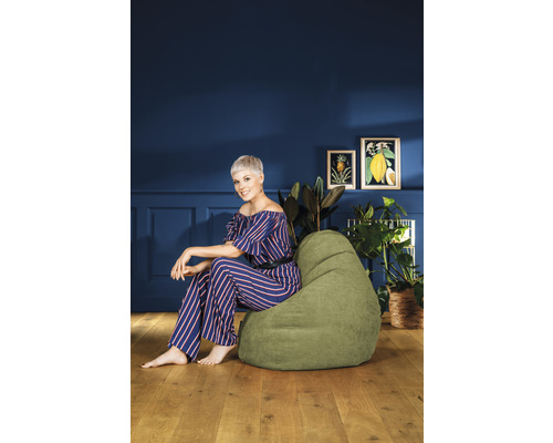 Frau sitzt auf einem grünen Sitzsack in einem Wohnzimmer