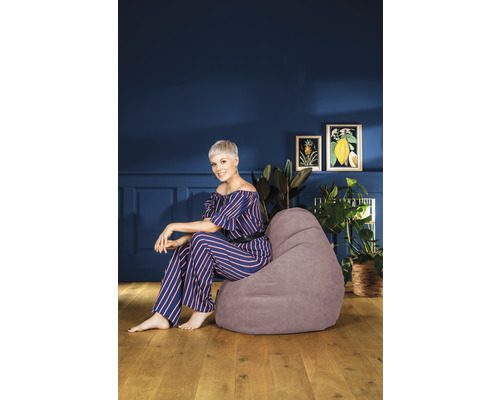 Frau sitzt auf einem grauen Sitzsack in einem Wohnzimmer