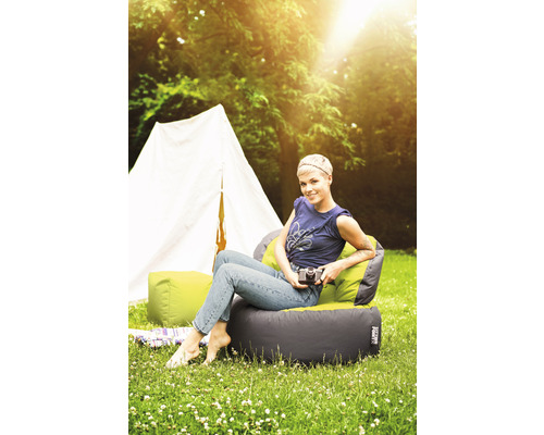 Szene mit einer Frau, die auf einem Sitzsackstuhl im Freien vor einem Zelt sitzt