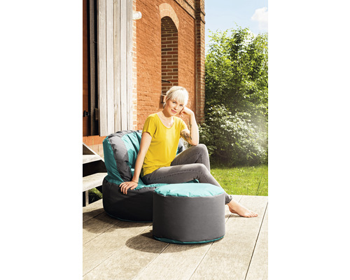 Frau sitzt auf Sitzsack mit Hocker im Garten.