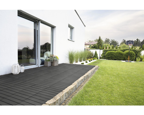 Terrasse mit Fliesen in einem Garten mit Rasen, Büschen und einem Basketballkorb