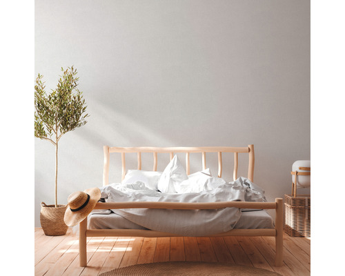 Helles Schlafzimmer mit Holzbett, Bettwäsche, Zimmerpflanze und Dekoration