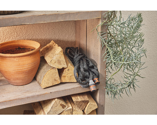 Holzregal mit Blumentopf, Brennholz, Gartenschlauch und Pflanze