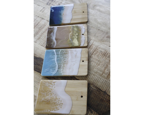 Vier Schneidebretter aus Holz mit Harzbeschichtung im Stranddesign.