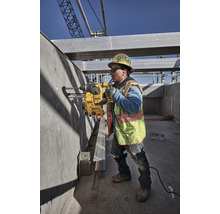 Ein Bauarbeiter bohrt mit einer Bohrmaschine ein Loch in eine Betonwand auf einer Baustelle.