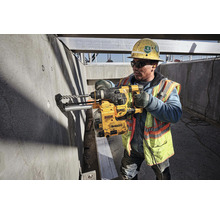 Ein Bauarbeiter bohrt mit einer DeWalt Bohrmaschine in eine Betonwand auf einer Baustelle.