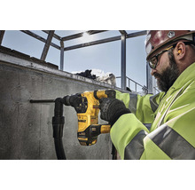 Ein Bauarbeiter bohrt mit einem Bohrhammer der Marke DeWalt ein Loch in eine Betonwand.