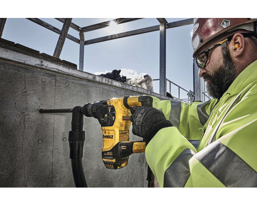 Ein Bauarbeiter bohrt mit einem Bohrhammer der Marke DeWalt ein Loch in eine Betonwand.