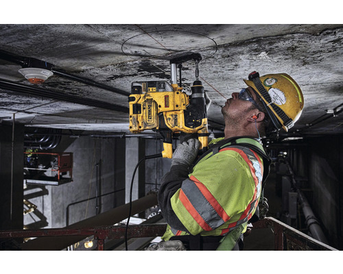 Ein Bauarbeiter bohrt mit einer Kernbohrmaschine von DeWalt ein Loch in eine Betondecke.