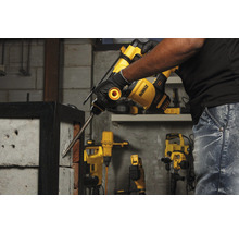 Ein Mann benutzt einen Bohrhammer von DeWalt, um in eine Ziegelwand zu bohren.