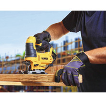 Eine Stichsäge beim Sägen eines Holzbretts, bedient von einer Person mit Arbeitshandschuhen