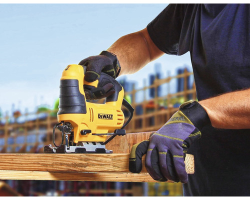 Eine Stichsäge beim Sägen eines Holzbretts, bedient von einer Person mit Arbeitshandschuhen