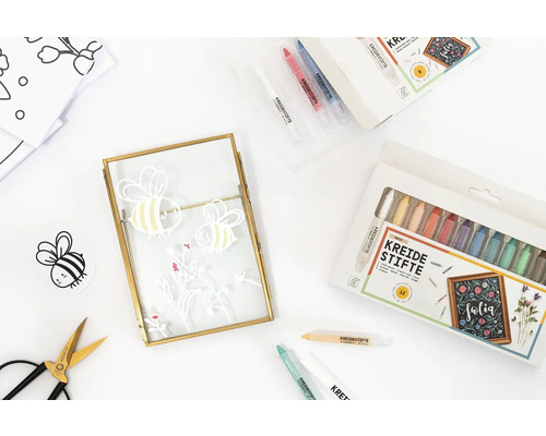 Szene mit Kreidestiften, Schere und Rahmen mit Bienenmotiven