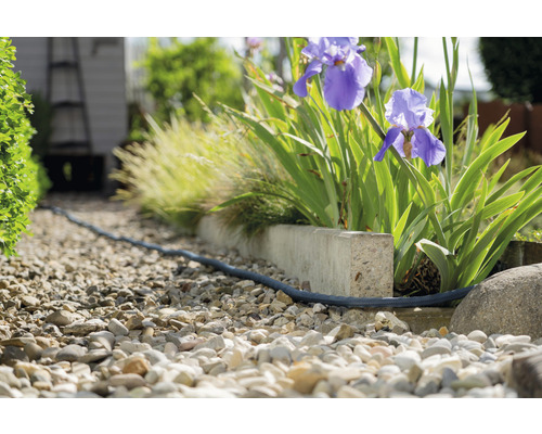 Gartenweg mit Kies und einem flexiblen Bewässerungsschlauch